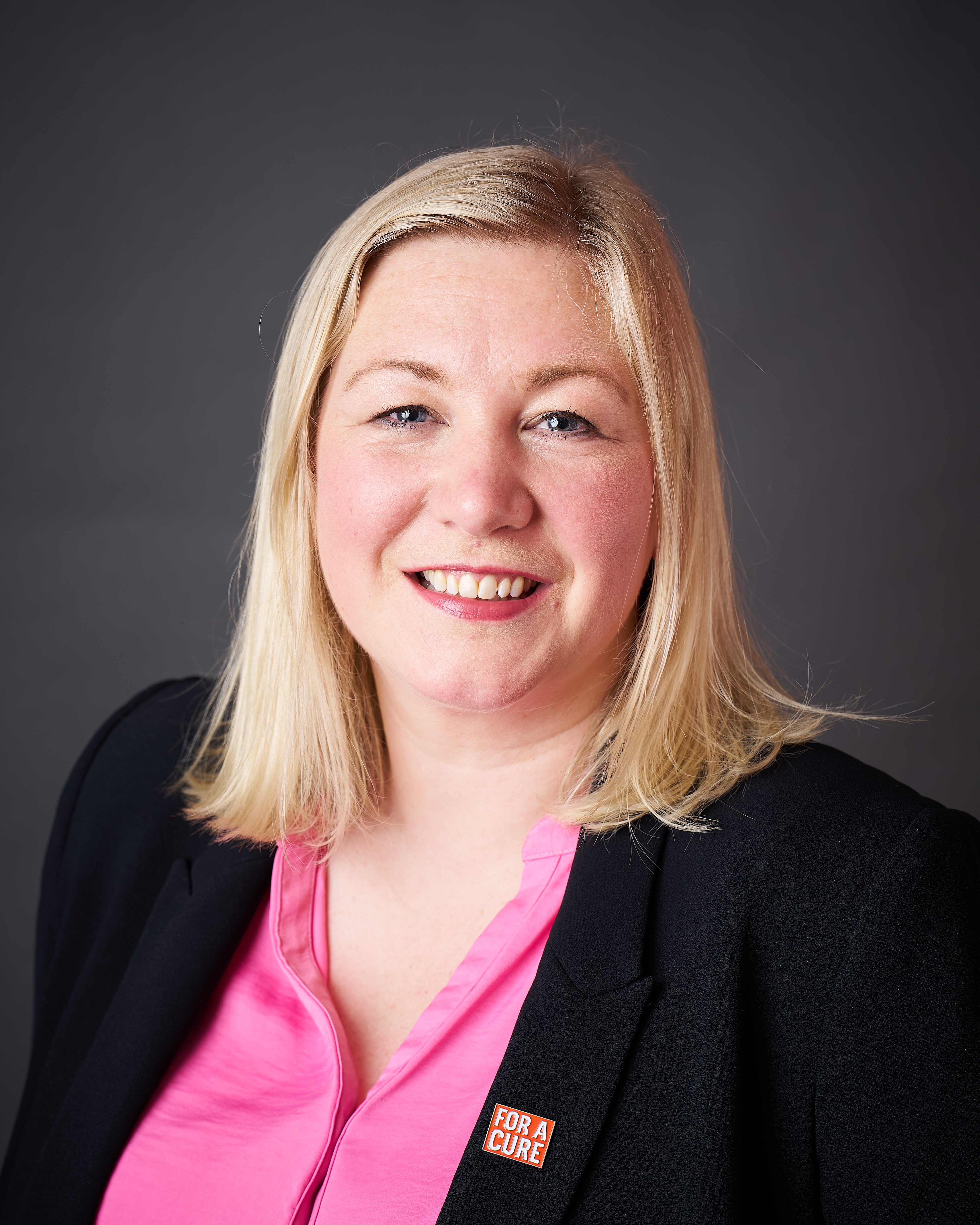 A photo of a woman with blonde hair looking directly at the camera and smiling