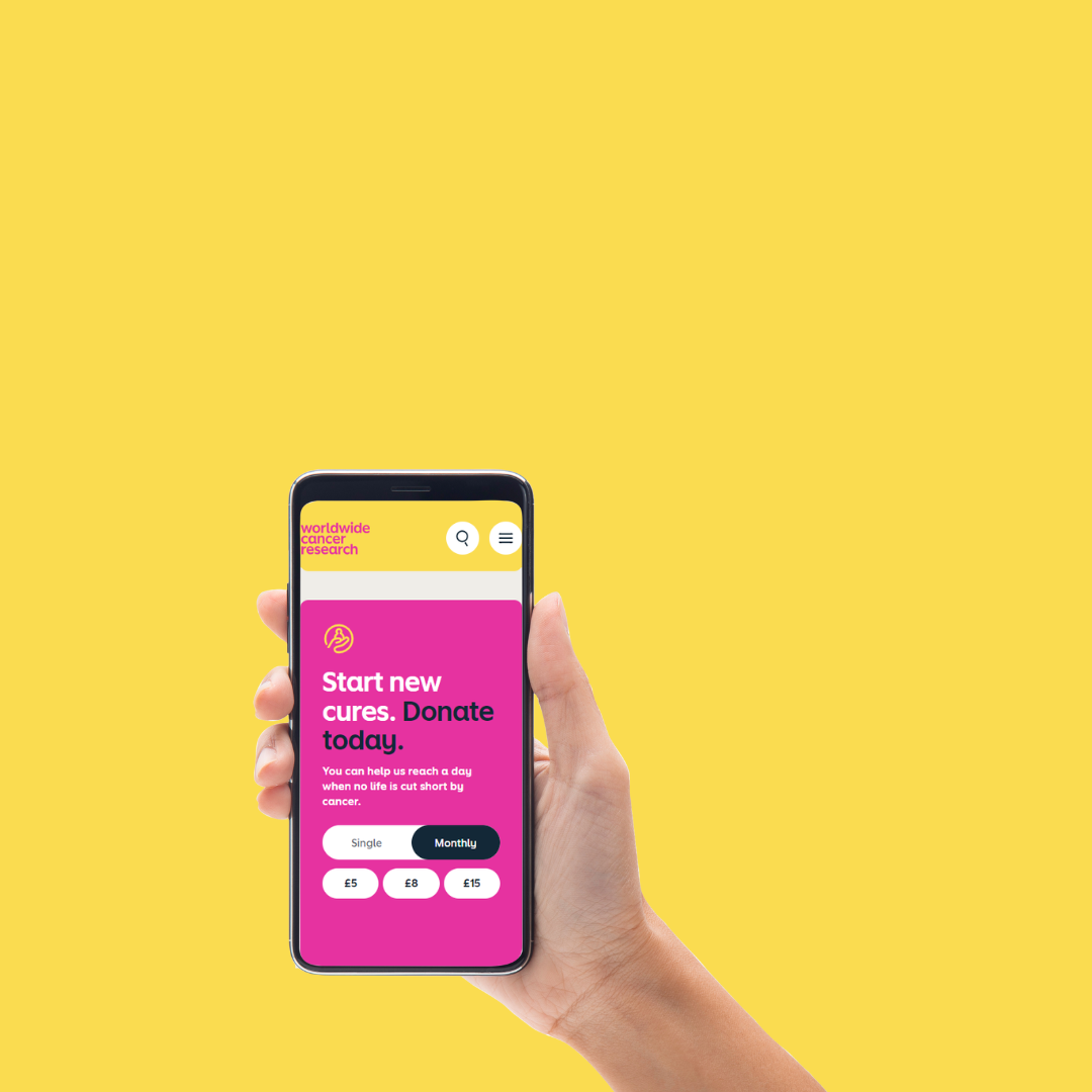 Hand holding smart phone browsing Worldwide Cancer Research website, on yellow background