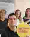 A selfie of Dr Eros Di Georgio's team of researchers holding a circular Worldwide Cancer Research logo