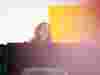 Someone standing laughing in an office against a yellow background