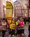 Man in a yellow t-shirt and flag running London Landmarks Half Marathon
